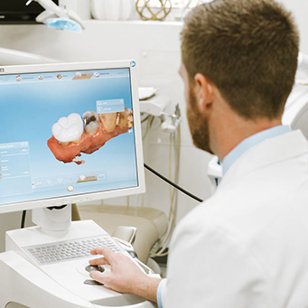 dentist looking at a dental implant model on a computer