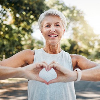 Lady smiles while making shape of a heart with hands