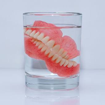 Dentures soak in glass with clear liquid