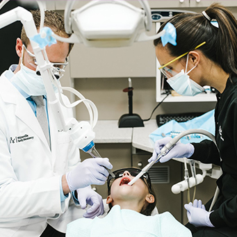 Dentist and team member treating young dental patient