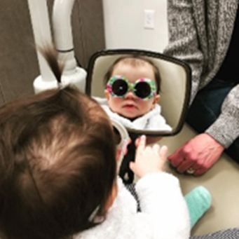 Small child looking in dental mirror