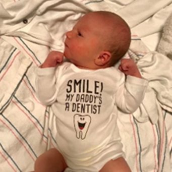 Baby with a onesie reading smile my dad's a dentist