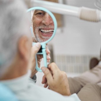 man smiling in small dental mirror   