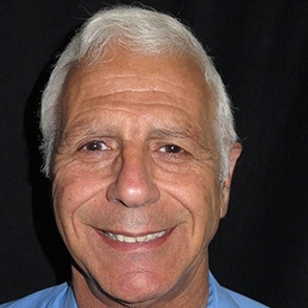 Man in blue shirt smiling with gray hair