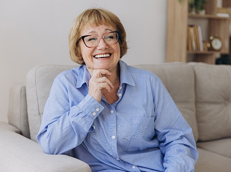 Woman in blue shirt smiling while sitting on couch