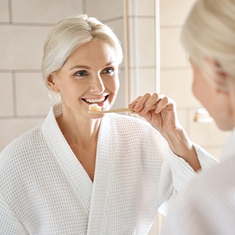 Woman smiling while brushing her teeth