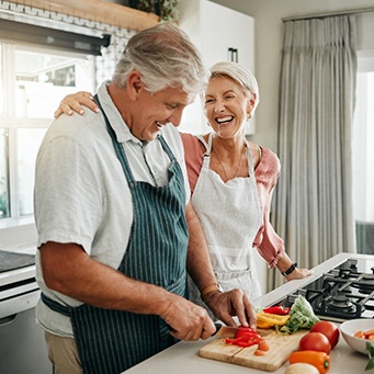 Couple smiling while preparing meal in kitchen