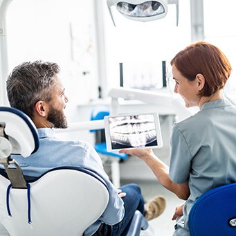 Patient and dentist reviewing X-ray on tablet