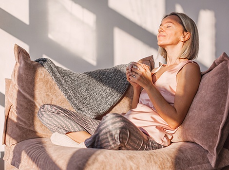 a woman relaxing on a couch with a cup of tea