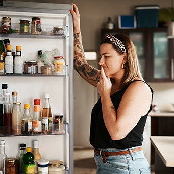 a woman looking inside her refrigerator