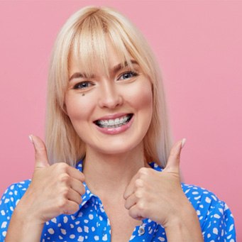 Woman smiling with clear braces and thumbs up