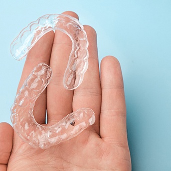 Patient holding clear aligners in the palm of their hand