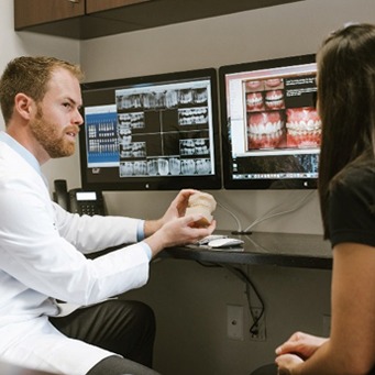 Dentist and dental patient looking at smile model and dental treatment computer software