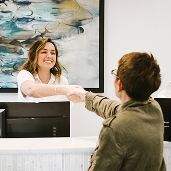 Smiling dental team member shaking hands with dental patient in Whitinsville