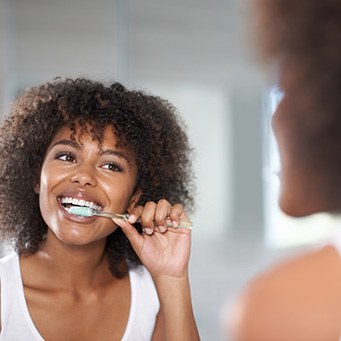 Woman smiling while brushing her teeth