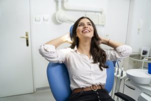 Woman smiling in dental chair after full mouth reconstruction in Whitinsville