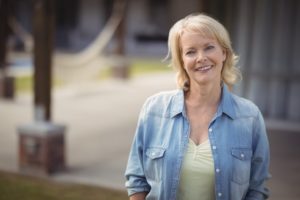 Older woman with denim shirt smiling outside 