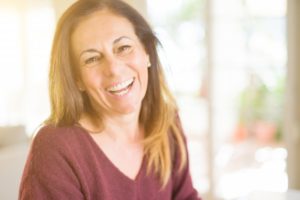 Older woman with arms crossed smiling with dentures