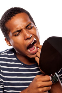 Concerned man checking tooth in a handheld mirror