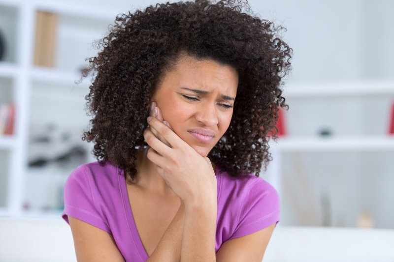 a woman having a dental emergency holding her jaw