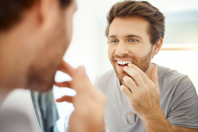 Patient smiling in the mirror after cosmetic dentistry